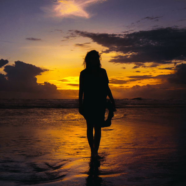 Image of woman standing in front of sun setting at beach